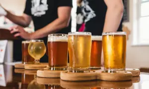 Assaggio di diverse birre artigianali in bicchieri su un tavolo di legno lucido.