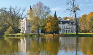 Pałac w Bolimowskim Parku Krajobrazowym odbija się w stawie, otoczony jesiennymi drzewami.