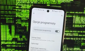 Telefon z włączonymi opcjami programisty na tle zielonego kodu.