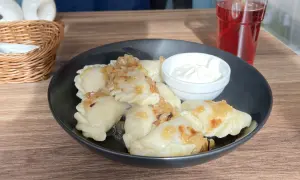 Leckeres Essen in Breslau: Dampfende Pierogi mit Zwiebeln und Sauerrahm, dazu ein rotes Getränk.