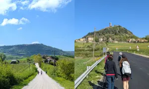 Pellegrini sulla Via Francigena, un cammino che porta verso un borgo arroccato su una collina, evocando il suo antico significato.