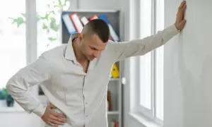 Mężczyzna opiera się o ścianę, czując silną nerwicę i objawy neurologiczne.