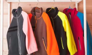 Kolorowe bluzy z polaru, w tym jeden plaszcz flausz, wiszą na wieszakach.
