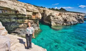 Frau genießt die Sonne an einer felsigen Küste mit türkisfarbenem Wasser. Perfekte pula unternehmungen für einen Urlaub.