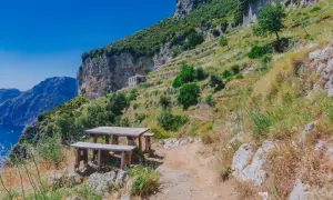 Un tavolo da picnic in legno attende i viaggiatori sul Sentiero degli Dei, con vista mozzafiato sul mare e sulle montagne.