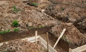 Wykonano wykopy pod fundamenty. Widać ziemię, drewniane szalunki i zbrojenie.