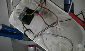 Rozmontowany bojler z widocznym termostatem i przewodami. Jak sprawdzić termostat w bojlerze? To zdjęcie pokazuje wnętrze, gdzie znajduje się element grzewczy i okablowanie.