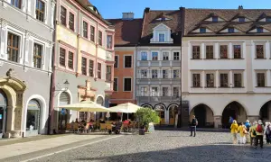 Café mit Außenbestuhlung auf einem historischen Platz mit bunten Häusern.