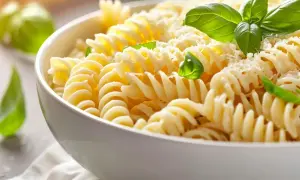 En skål med fusilli-pasta, toppad med riven ost och färsk basilika. Perfekt för ett snabbt pastasås recept.