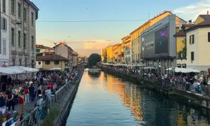 Tętniące życiem Navigli w Mediolanie. Ludzie spacerują wzdłuż kanału, ciesząc się wieczornym słońcem i atmosferą.