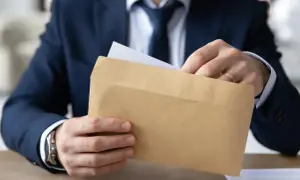 Mężczyzna w garniturze wkłada dokument do brązowej koperty. Czy odpowiedź na apelację doręcza się bezpośrednio pełnomocnikowi?