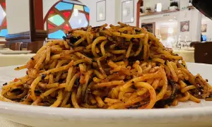 Un piatto di spaghetti con pomodoro e basilico, un classico del cibo barese, servito in un ristorante con vetrate colorate.