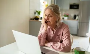 Femme âgée réfléchissant devant son ordinateur, cherchant des solutions pour savoir que faut il faire pour ne pas payer une maison de retraite.