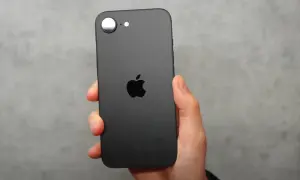Czarna obudowa iPhone SE 4 z charakterystycznym jabłkiem Apple. Telefon trzymany w dłoni na szarym tle.