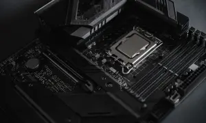 Czarna płyta główna z procesorem i slotami RAM. Widoczny radiator i elementy chipsetu.