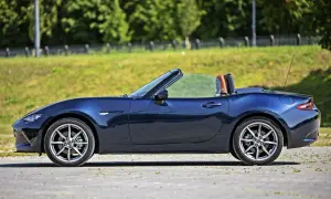 Granatowy roadster z otwartym dachem, gotowy na letnią przejażdżkę pośród zieleni.