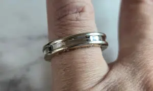 Anillo Bulgari de oro blanco y detalles pulidos, adornando un dedo con su diseño elegante y atemporal.