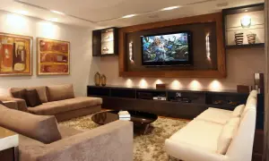 Accogliente soggiorno con divani, TV e quadri. Soluzioni d'arredo per una stanza senza finestra, creando un'atmosfera luminosa e moderna.