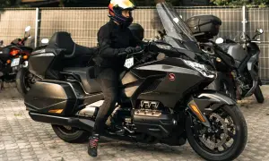 Kobieta w kasku na potężnym motocyklu turystycznym, obok inne rodzaje motocykli.