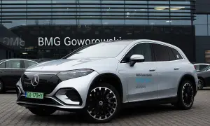 Srebrny Mercedes EQS SUV z napisem "BMG Goworowski EQS SUV jazda testowa" przed salonem samochodowym.