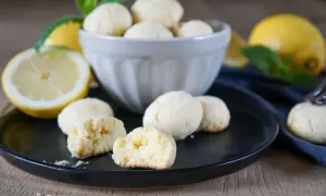 Zitronenkekse italienisch: zarte, helle Kekse mit frischen Zitronen und Minze auf schwarzer Platte.