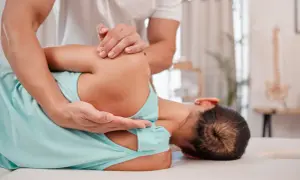 Fizjoterapeuta pomaga pacjentce zmagającej się z neurologiczne bóle mięśni, wykonując delikatny masaż barku.
