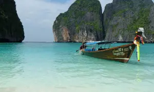 Łódź kołysze się na turkusowej wodzie w zatoce Maya Bay, Tajlandia, otoczonej stromymi klifami.