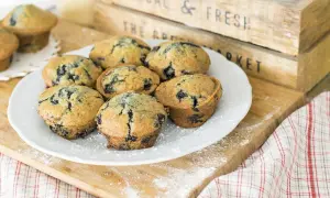 Plate of delicious muffin myrtille, sprinkled with powdered sugar, on a wooden board.
