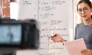 Nauczycielka wyjaśnia matematykę przed kamerą, pokazując, co to jest nauczanie hybrydowe.