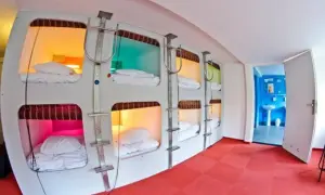 Wnętrze hotelu kapsułowego w Japonii z rzędami łóżek w kolorowych kapsułach.