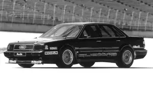 Czarny Audi 5000 Quattro na torze wyścigowym, z logotypami Boge, Michelin i Shell.