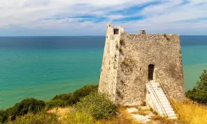 Torre costiera in pietra con mare turchese sullo sfondo, un luogo suggestivo tra i tanti posti da visitare in Puglia.
