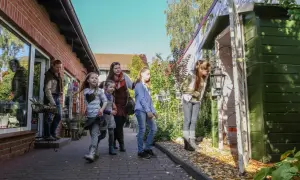 Familie erkundet die Templin Altstadt, vorbei an einem roten Backsteinhaus und einem grünen Schuppen mit Laterne.