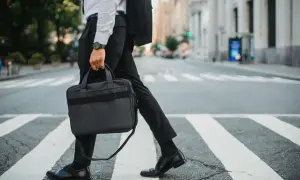Biznesmen w garniturze idzie przez pasy, niosąc teczkę. Może właśnie wraca z pracy, myśląc o swojej **dieta krajowa**.