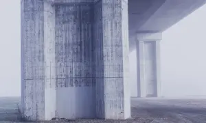 Monumentalne filary mostu, prezentujące różne klasy ekspozycji betonu, toną we mgle.