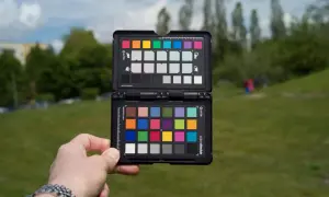 Dłoń trzyma otwartą kartę X-Rite ColorChecker, aby ustawić prawidłową temperaturę barwową w plenerze.