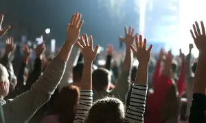 Tłum z rękami w górze, jakby na koncercie lub spotkaniu sekty.
