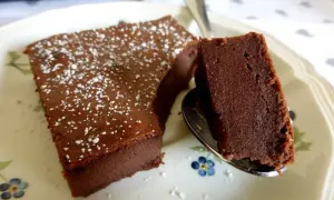 Un délicieux gâteau chocolat mascarpone facile, saupoudré de sucre glace, servi sur une assiette fleurie.