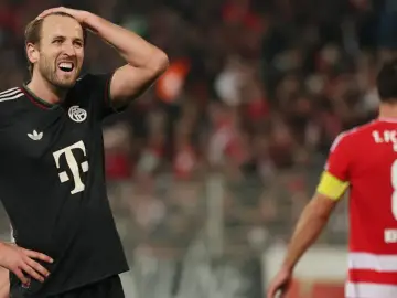 Piłkarz Bayernu w czarnej koszulce z T na piersi, z ręką na głowie, w meczu przeciwko Union Berlin.