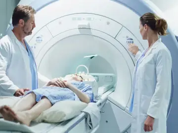 Pacjentka leży w aparacie do rezonansu magnetycznego, a lekarze przygotowują badanie z kontrastem.