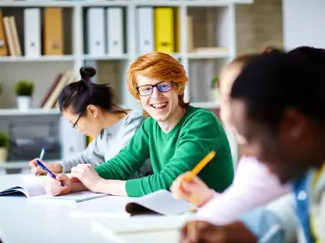 Uśmiechnięty rudowłosy student cieszy się z możliwości nauki. Szkoła policealna online za darmo otwiera drzwi do wiedzy dla każdego.