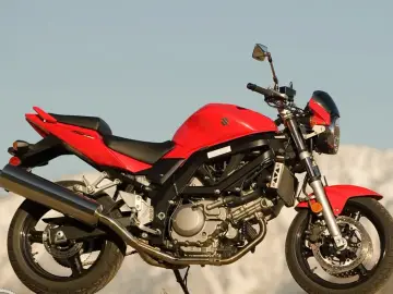 Czerwony motocykl Suzuki SV 650 na tle nieba i gór.