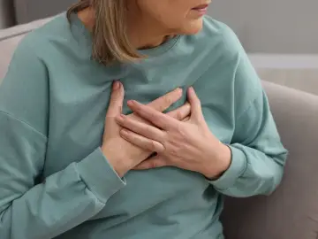Kobieta trzymająca się za serce. Badanie poziomu lipoproteiny jest kluczowe dla oceny ryzyka chorób serca.