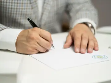 Mężczyzna w eleganckim garniturze podpisuje porozumienie zmieniające warunki pracy i płacy.