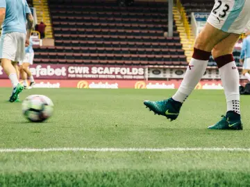 Piłkarz angielskiego klubu piłkarskiego kopie piłkę na boisku.