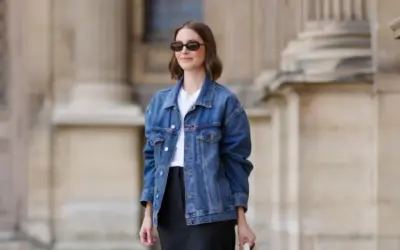 Donna con occhiali da sole indossa un outfit giacca jeans donna, t-shirt bianca e gonna nera.
