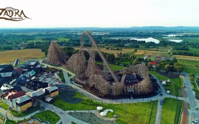 Drewniany rollercoaster Zadra w parku rozrywki, z widokiem na okoliczne pola i jeziora. Zastanawiasz się, ile jedzie Zadra?
