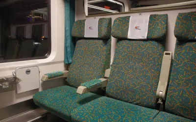 Wygodne siedzenia w wagonie bezprzedziałowym PKP Intercity. Wzór na tapicerce przypomina falujące linie.