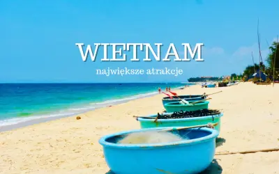 Niebieskie łodzie na piaszczystej plaży Wietnamu z turkusowym morzem w tle.