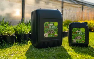Dwa czarne kanistry z napisem "Dżo Humus" - naturalny nawóz stworzony przez dżdżownice, który wspomaga wzrost roślin.